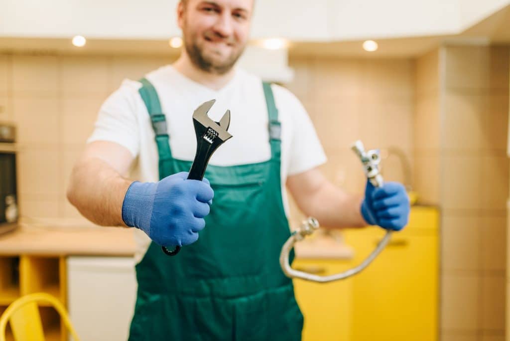 Plumber in uniform holds wrench, handyman
